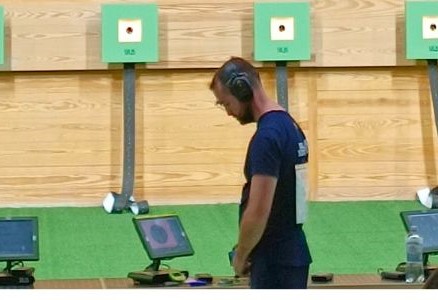 Bosnian sport shooter Boris Filipovac standing alone on the shooting line, seemingly deep in thought, perhaps battling performance pressure, with a line of targets in the background.