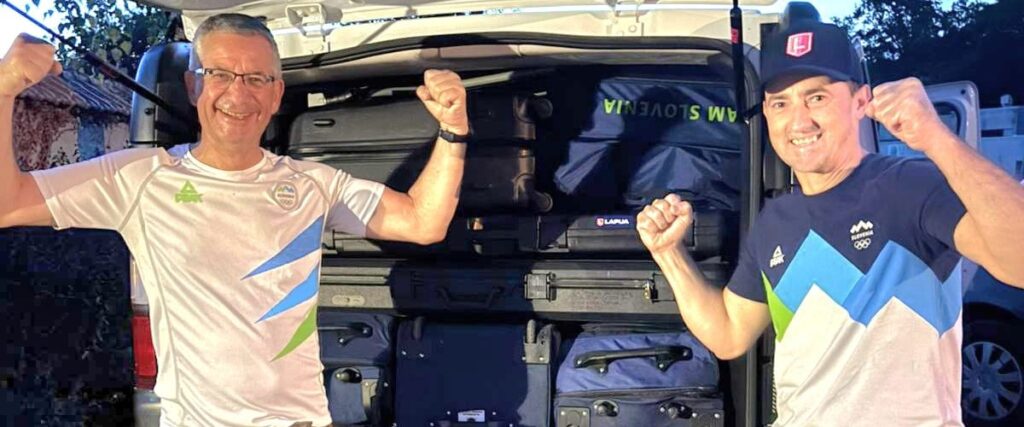 Slovenian sport shooters Rajmond Debevec and Robert Markoja standing victorious in front of a van completely full of shooting equipment
