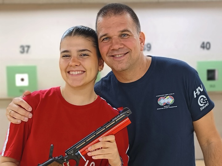 Serbian shooting coach Goran Mikec (right) with daughter, pistol shooter Tea MIkec (left) holding a pistol.