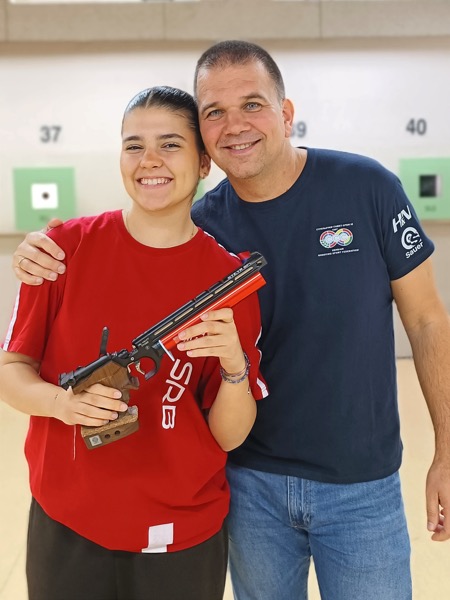 Serbian shooting coach Goran Mikec (right) with daughter, pistol shooter Tea MIkec (left) holding a pistol.